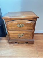 Front view of one wooden bedside table showing two drawers and brass-tone pulls