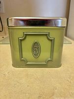 Green metal canister with letter T