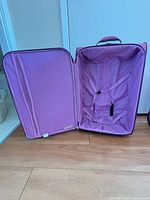 Open interior of one Millennium pink suitcase showing striped lining and tie-down straps