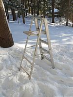 Full side view of folded aluminum ladder in snow
