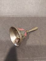 Brass bell on side showing interior and rusted clapper, enamel band visible
