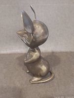 Side profile of brass mouse figurine showing shape and patina