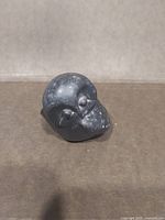 Front angled view of carved stone owl showing eyes, beak and speckled surface