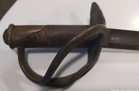 Close-up of hilt showing leather grip and brass three-bar guard