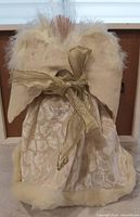 Back view of ivory angel tree topper with faux-fur cape and gold ribbon