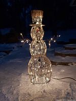 Lighted twig snowman illuminated at night showing lights and cord