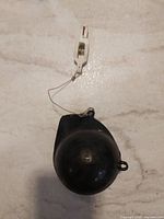 Black plastic float attached to wire and plastic clip