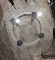 Top view of one glass table showing circular glass and leg positions