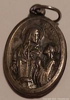 Front of oval medal showing Saint Anne with Virgin Mary and Child, jump ring visible