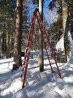 Side view of 12-ft orange fiberglass A-frame ladder standing in snow