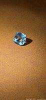 Cushion-cut light blue aquamarine resting on surface