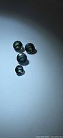 Four round green-blue sapphires arranged on light background