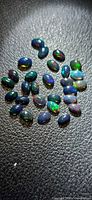 Group of oval black opal cabochons showing play-of-colour