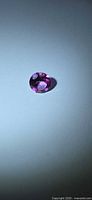 Round faceted hot pink topaz on neutral background