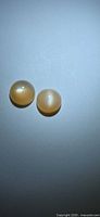 Two round peach moonstone cabochons on neutral background