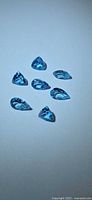 Seven Swiss blue topaz stones arranged on neutral background