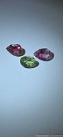 Three faceted tourmaline stones on neutral background showing colour and cut