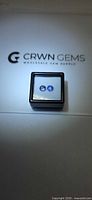 Matched pair of round tanzanites in display case on CRWN GEMS background