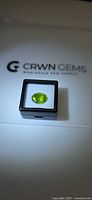 Oval vivid green peridot in display case on CRWN GEMS backing