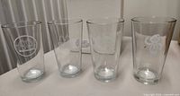 Front view of four clear pint glasses with different McDonald’s etched designs