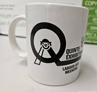 White ceramic Quinte Exhibition mug showing logo
