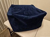 Overall view of navy velvet cube pouf on table