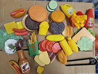 All play food pieces spread on cardboard, showing variety and wear