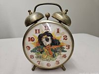 Front view showing cartoon lion dial, numerals, red body, brass bells