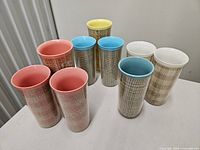 Nine tall plastic tumblers with varied interior colours displayed on table