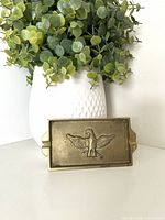 Front view of rectangular brass ashtray displaying eagle motif and patina