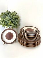 Stacked set of Denby Rust Red plates with one plate on stand