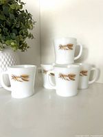 Five white milk glass mugs with wheat pattern grouped