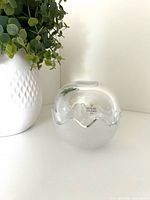 Clear and frosted bowls nested to show spherical form with sticker visible