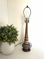 Full view of lamp without shade next to plant for scale