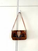 Front view of suede patchwork purse hanging by strap