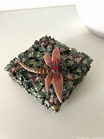 Top view of closed trinket box showing floral enamel and dragonfly with crystals