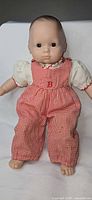 Front view of Bitty Baby doll standing in red gingham overalls and ivory blouse