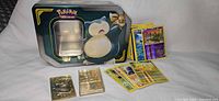 Overall lot showing Snorlax tin, metal cards, stack of loose cards with holographics