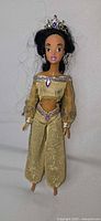 Front view of Princess Jasmine doll in gold outfit with tiara and earrings