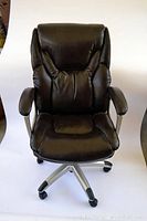 Front view of black leather office chair showing padded seat, backrest, and armrests with silver base on wheels.
