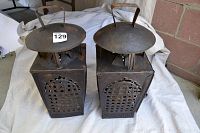 Two square outdoor metal lanterns side by side showing the top handles and perforated pattern on sides.