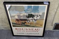 Framed Rousseau Dit Le Douanier art poster showing horse and carriage with people, text includes Galerie Charpentier and date 1961, displayed leaning against wall.