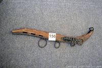 Top view of a vintage wooden horse hame with metal hardware on a gray carpet.