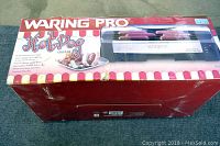 Photo of the Waring Pro Hot Dog Roller Grill retail box from top angle showing branding, image of product, and key product features.