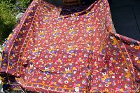 Full view of large handmade bedspread with floral pattern spread outdoors to show size and detail.