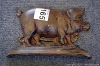 Metal pig-shaped door stop shown from the side, displaying detailed sculpting and weathered finish.