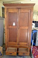 Full view of the antique wooden wardrobe with double doors and two bottom drawers open