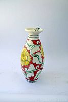 Front and side view of the vase showing floral painted detail in yellow, red, green, and white.