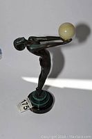 Side view of statue with extended arms holding globe