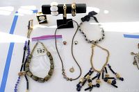 Photo showing a broad selection of contemporary jewelry including large bead necklaces, gold-tone link necklaces, large white bracelets, rings, and a watch.